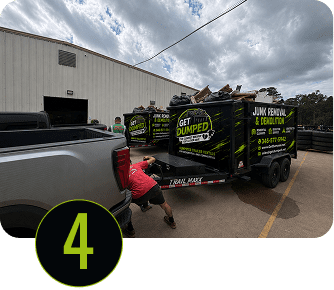 Worker hitching branded junk-removal trailer to pickup